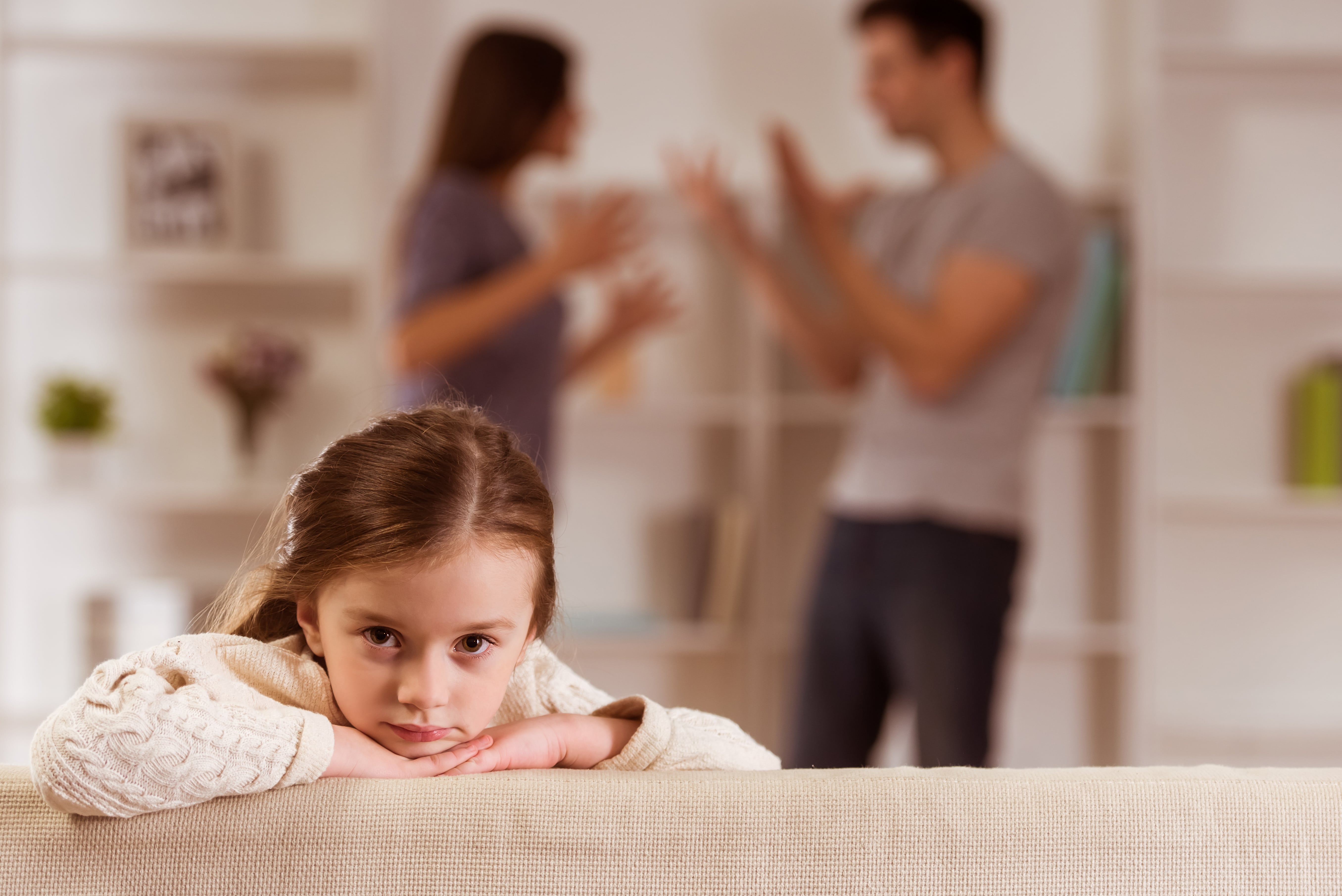 young girl with parents arguing behind her